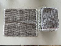 Stack of folded dark and light woven place mats with fine woven texture, black and white pattern