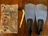Two translucent blue swim fins with black foot pockets, yellow and black snorkel, and plastic packaging