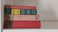 Stack of five hardcover books shown with visible titles on spines: Wuthering Heights, Rebecca, Doctor Zhivago, and other titles.