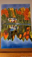 Front image of the decorative ceramic tile with a fall cottage on the lake scene.