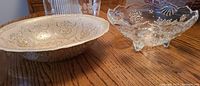 Photo of two serving bowls on wood table, one ornate Turkish glass bowl with gold pattern and one clear cut crystal bowl with floral motifs.