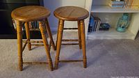 Pair of solid oak stools showing overall shape, legs, and finish.