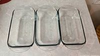 Three clear rectangular glass baking dishes lined up side by side, top view.