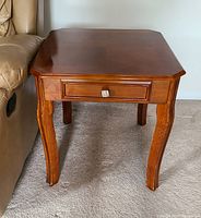 Front view showing table top, decorative false drawer, and curved legs.