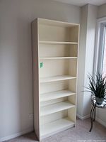 Front angled view of the white bookshelf showing five shelves and adjustable shelf holes.