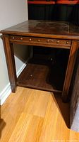 Front side view of dark wooden end table showing lower shelf and decorative studs under top surface.