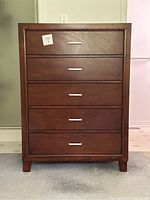Full front view of the dresser showing five drawers, mahogany finish and metal handles.