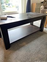 Side angle view of coffee table showing rough sawn pine top and sturdy legs with dark stain