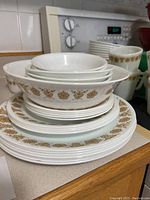 Stack of plates and bowls showing gold floral butterfly pattern around edges on white ceramic.