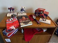 Overview of Montreal Canadiens hockey collectibles on a wooden dresser including figurines, signed puck, book, scarf, and coin bank