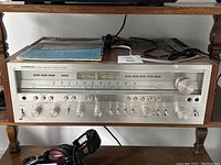 Front view of Pioneer SX-1250 stereo receiver on shelf with cables and headphones