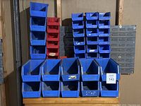 Wide view showing an assortment of blue and red plastic stackable bins in various sizes arranged on shelving.