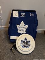 Blue Toronto Maple Leafs cooler backpack with lace-up detail on front and logo displayed. Cooler backpack sits upright on carpeted floor.