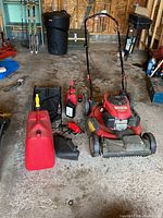 Full lot showing mower, gas can, oil bottle, JumpStart starter and grass bagger parts