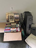 Photo showing the Proscan VCR player next to a box of 34 classic VHS tapes including titles like Gladiator, The Mask, and Ghost Dad