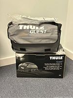 Thule Quest rooftop bag on top of its original box featuring product name and branding.