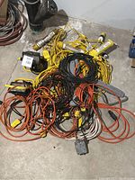 Top down view of assorted electrical cords and power bars on floor, cords are tangled together