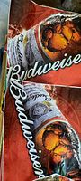 Close-up photo showing two unused large square decals featuring Budweiser beer bottle and branding on a red background.