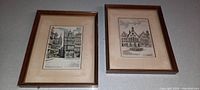 Both framed art pictures showing old German buildings, wooden frames and beige mats