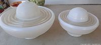 Two mid century glass light globes, 10 inch and 6 inch, placed side by side on table showing size difference and ribbed clear design.