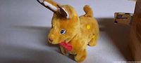 Photo of the plush toy reindeer showing light brown fur, white spots, red bow tie, and upright tail
