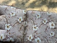 Close-up photo showing floral print detail on the chair cushions with tan background and large flowers with leaves.