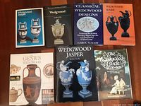Seven hardback books arranged on a wooden surface showing titles related to Wedgwood Jasper and pottery.