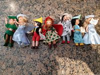 Full view of the seven McDonald Happy Meal dolls arrayed side by side on countertop showing various characters and outfits.