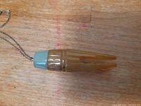 Close-up of the Buddha hands agate pendant with light green jade-like cap on chain laid on wooden surface