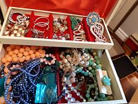 Box of assorted vintage jewelry items including necklaces, earrings, brooches and rings in compartmentalized box with red insert