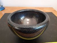 Front angled view of the black glass bowl showing texture and flecks pattern on surface.