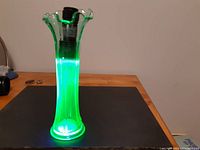 Front angle showing the entire vase glowing green under UV light on a surface