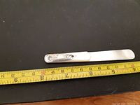 Full length of mother of pearl bookmark with sterling silver decorative end, placed against a measuring tape showing length of about 3.5 inches.