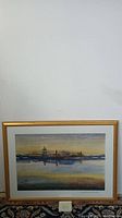 Complete view of the framed painting showing the architectural landscape and water reflection with gold frame.