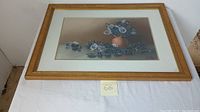 Horizontal photo of the framed floral bouquet painting taken from above, showing full artwork and frame.