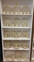 Full shelving unit displaying multiple place settings of plates, cups and one platter