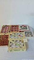 Overall view of seven boxes of assorted vintage glass Christmas ornaments in original packaging from Coby, Holly, and Pyramid showing various colors and styles