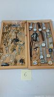 Full view of assortment of keys and wrist watches arranged in wooden trays.