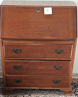 Front view of vintage Maddox slant front secretary desk, showing three drawers and drop-front panel.