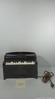 Front view of the black vintage Magnus electric organ showing keyboard and shape.
