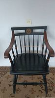 Full frontal view of the vintage wooden chair showing black paint with gold and brown accents, and VE RE TAS emblem on top backrest.