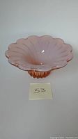 Side angle view showing scalloped edge and pink opalescent glass dish shape and ridged base