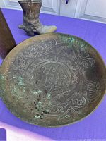 Photo showing brass etched bowl with Asian style dragon and floral designs and western boot figurine in background.