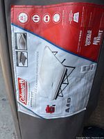 Close-up photo of Coleman label on carrying bag showing product details of queen size airbed camping cot frame and cover.
