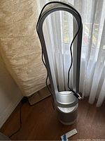 Full-height view of fan showing loop amplifier, perforated base, power cord and remote on floor