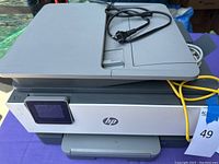 Top and front angled view of HP OfficeJet Pro 9015 all-in-one printer showing touchscreen and scanner flatbed lid with power cable coiled on top.