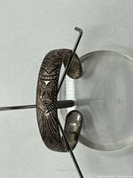Angle view of the engraved sterling silver bracelet showing the full length with stylized face and geometric patterns