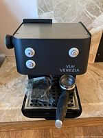 Front view of Via Venezia espresso machine showing three white round buttons and portafilter attached.