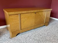 Front and angled view of the vintage oak blanket chest showing wood grain, lock, and carved vertical accents