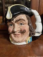 Front view of the Royal Doulton Captain Henry Morgan toby mug showing detailed facial features and black tricorn hat with white trim and feather accents.
